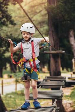 Mutlu çocuk yaz günü tırmanma parkında eğleniyor.