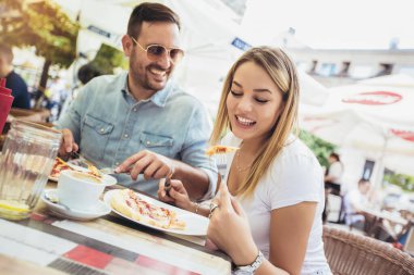 Pizzada eğlenen, birlikte eğlenen genç çiftin fotoğrafı.. 