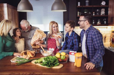 Üç kuşak aile mutfakta yemek hazırlıyor, eğleniyorlar.