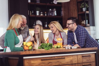 Üç kuşak aile mutfakta yemek hazırlıyor, eğleniyorlar.