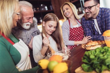 Üç kuşak aile mutfakta yemek hazırlıyor, eğleniyorlar.