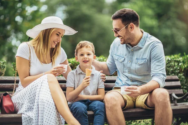 Genç mutlu aile haftasonunu parkta dondurma yiyerek geçiriyor..