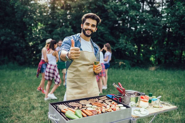 Man preparing barbecue for friends outdoor