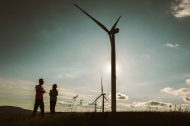 Rüzgar türbinindeki mühendislerin silueti elektrik endüstrisi