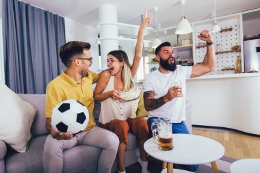 Bir grup genç arkadaş evde futbol maçı izliyor, tezahürat yapıyor ve bira içiyorlar..