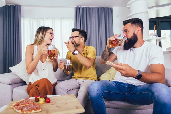Bir grup genç birlikte eğleniyor. Bira ve pizzayla aydınlık bir odada oturmak..