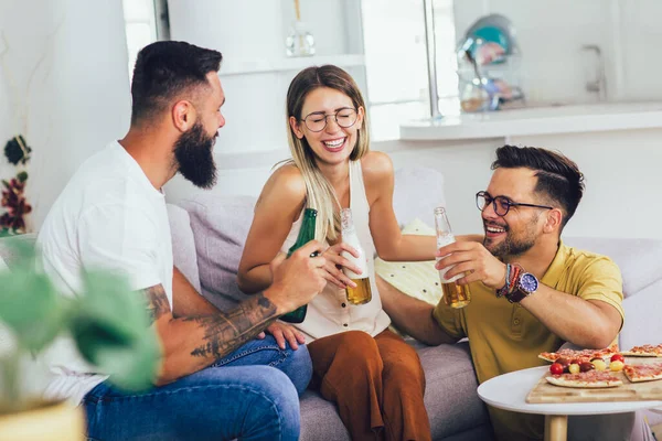 Bir grup genç birlikte eğleniyor. Bira ve pizzayla aydınlık bir odada oturmak..