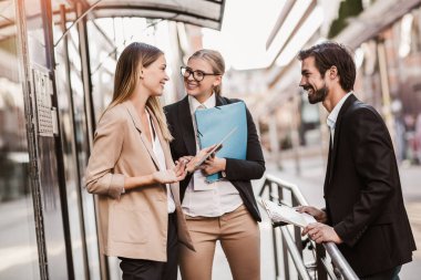 Ofisteki iş arkadaşları ofis binasının yanında konuşuyor, yeni projeyi tartışıyorlar, pano ve dijital tableti tutuyorlar..