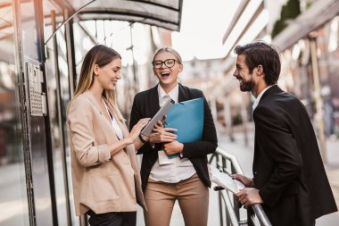 Ofisteki iş arkadaşları ofis binasının yanında konuşuyor, yeni projeyi tartışıyorlar, pano ve dijital tableti tutuyorlar..