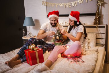 Genç çift evde bir Noel ağacı süslüyor.