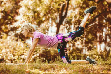 Park 'ta yoga egzersizi yapan yaşlı bir kadın..