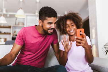 Evde akıllı telefonu olan Afrikalı bir baba ve kız.