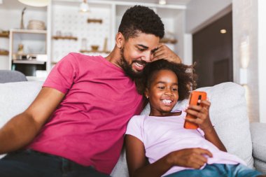 Evde akıllı telefonu olan Afrikalı bir baba ve kız.