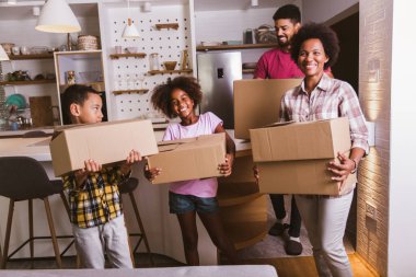 Gülümseyen aile taşınma gününde yeni eve kutu taşıyor..