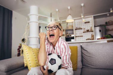 Yaşlı kadın duygusal olarak televizyonda futbol seyrediyor ve zaferi evde kutluyor..