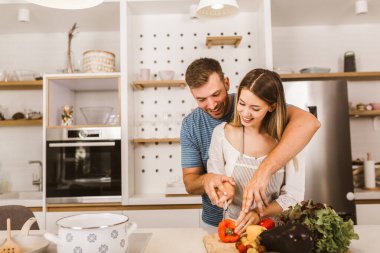 Genç çift mutfakta birlikte yemek pişiriyor.