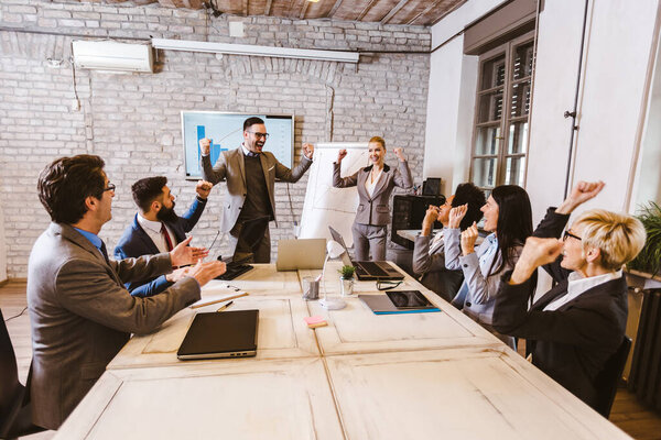 Group of happy colleagues talking while having business meeting in the office.