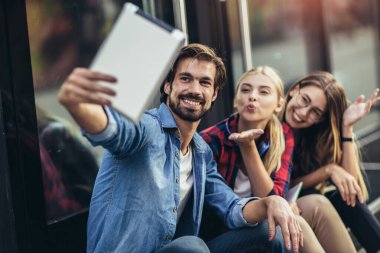 Bir grup arkadaş tabletle selfie çekiyorlar.