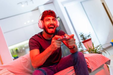 Genç bir adam elinde bir kumandayla evde oturuyor ve ekranına odaklanmış, tamamen oyuna dalmış, sanal maceralardan ve zorluklardan zevk alıyor. Kırmızı ışık