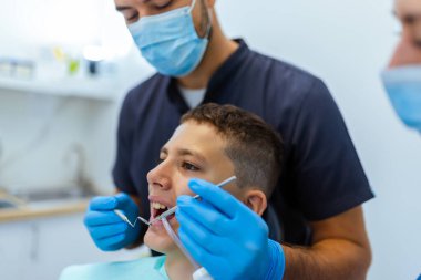 Küçük çocuk modern bir klinikte dişçi dişlerini muayene etmeye ve onarmaya hazırlanırken, çocuk sağlığı ve profesyonel tedaviyi gösteriyor..