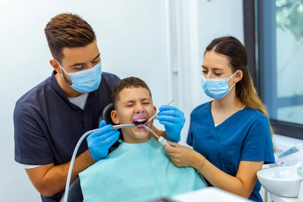 Modern bir diş kliniğinde korkmuş bir çocuğu iki diş hekimi tedavi ediyor. Doktorlar tıbbi bakım ve diş hekimliği pratiğini ön plana çıkarırken çocuk acı çekiyor..