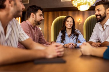 Bir grup arkadaş birlikte gülüyor ve eğleniyorlar modern kafede, neşeli ve hayat dolu sosyal ortamlarda.