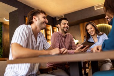 Modern kafede bir grup genç arkadaş tabletten bir şeyler izleyip gündelik sosyal anın tadını çıkarıyorlar..