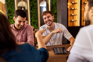 Modern kafede bir grup genç arkadaş tabletten bir şeyler izleyip gündelik sosyal anın tadını çıkarıyorlar..