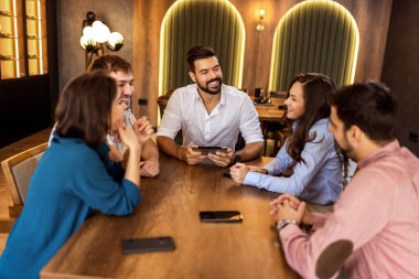 Modern kafede bir grup genç arkadaş tabletten bir şeyler izleyip gündelik sosyal anın tadını çıkarıyorlar..