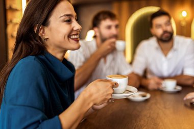 Bir grup genç arkadaş modern kafede eğleniyor, sohbet ediyor ve sosyal ortamlarda rahatlıyorlar..