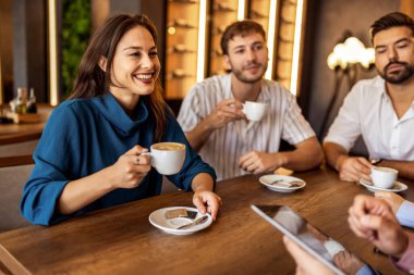 Bir grup genç arkadaş modern kafede eğleniyor, sohbet ediyor ve sosyal ortamlarda rahatlıyorlar..