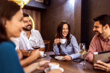 Bir grup genç arkadaş modern kafede eğleniyor, sohbet ediyor ve sosyal ortamlarda rahatlıyorlar..