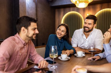 Bir grup genç arkadaş modern kafede eğleniyor, sohbet ediyor ve sosyal ortamlarda rahatlıyorlar..