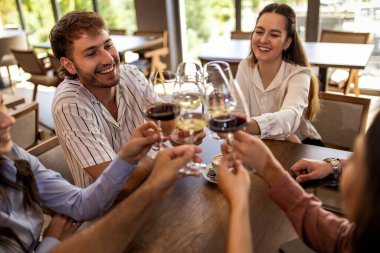 Modern kafede kadeh kaldıran bir grup genç arkadaş.