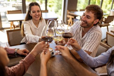 Modern kafede kadeh kaldıran bir grup genç arkadaş.