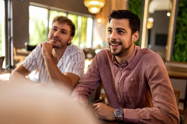 Bir grup arkadaş birlikte gülüyor ve eğleniyorlar modern kafede, neşeli ve hayat dolu sosyal ortamlarda.