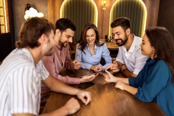 Modern kafede bir grup genç arkadaş tabletten bir şeyler izleyip gündelik sosyal anın tadını çıkarıyorlar..
