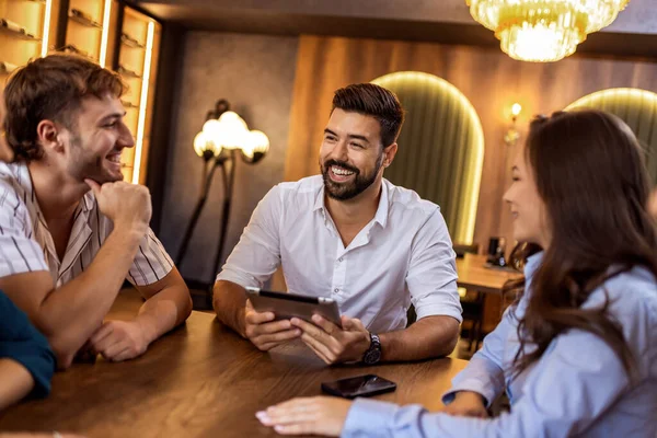 Modern kafede bir grup genç arkadaş tabletten bir şeyler izleyip gündelik sosyal anın tadını çıkarıyorlar..