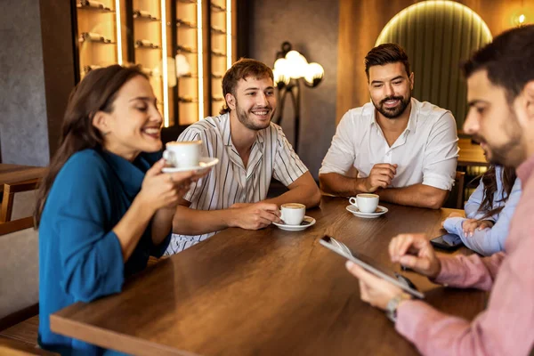 Bir grup genç arkadaş modern kafede eğleniyor, sohbet ediyor ve sosyal ortamlarda rahatlıyorlar..