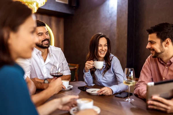 Bir grup genç arkadaş modern kafede eğleniyor, sohbet ediyor ve sosyal ortamlarda rahatlıyorlar..
