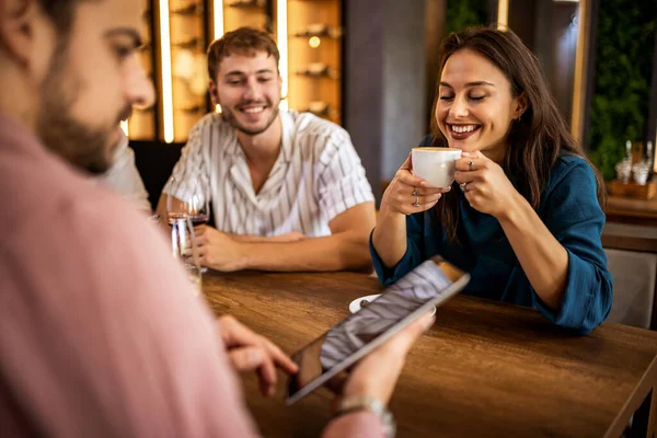Bir grup genç arkadaş modern kafede eğleniyor, sohbet ediyor ve sosyal ortamlarda rahatlıyorlar..
