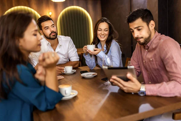 Bir grup genç arkadaş modern kafede eğleniyor, sohbet ediyor ve sosyal ortamlarda rahatlıyorlar..