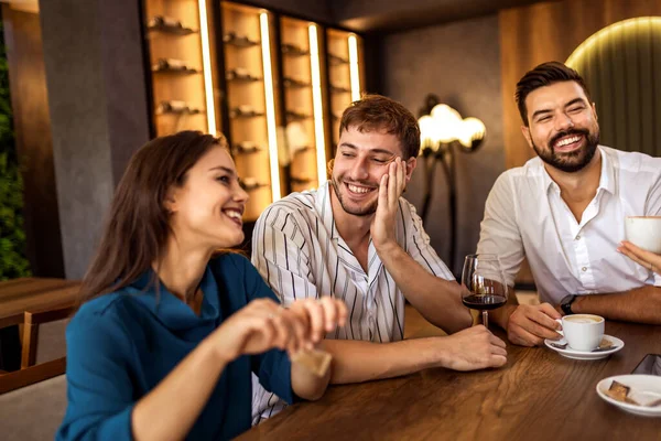 Bir grup genç arkadaş modern kafede eğleniyor, sohbet ediyor ve sosyal ortamlarda rahatlıyorlar..