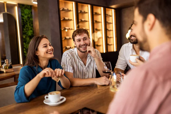Bir grup genç arkadaş modern kafede eğleniyor, sohbet ediyor ve sosyal ortamlarda rahatlıyorlar..