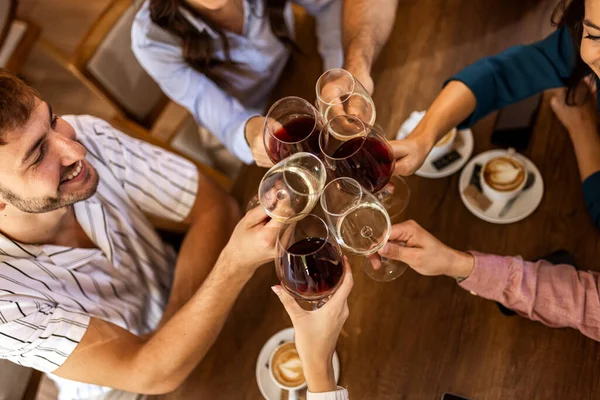 Modern kafede kadeh kaldıran bir grup genç arkadaş.