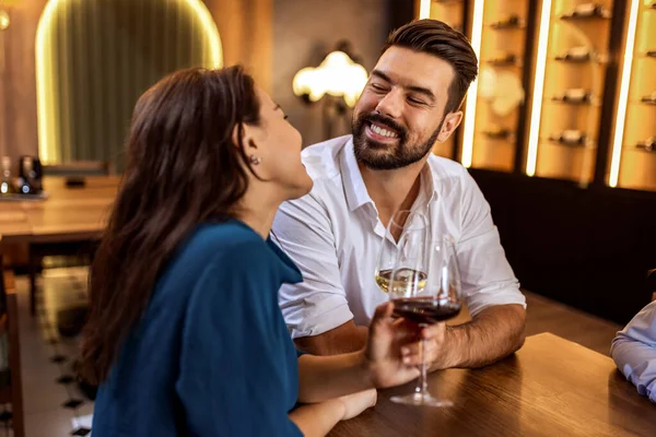 Modern kafede ellerinde şarap kadehleriyle gülümseyen genç bir çift gündelik ve neşeli bir anı paylaşıyor..