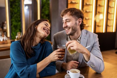 Gülümseyen genç çift meyve suyu ve kahvenin tadını çıkarıyorlar rahat modern bir kafede, yaşam tarzında ve boş zamanlarında..