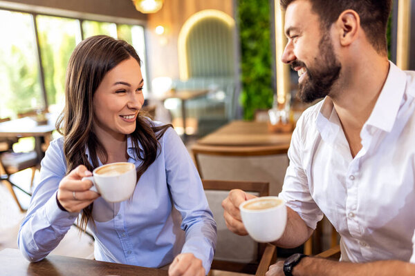 Relaxed young couple enjoying coffee together in cozy modern cafe, casual lifestyle moment.