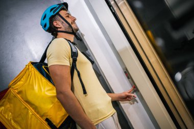 Teslimat kuryesi paketle birlikte asansörün önünde duruyor, ulaşım konsepti, lojistik, kurye işi, modern şehir yaşam tarzı, hızlı servis.