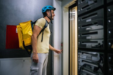 Paketi olan kurye asansörün önünde duruyor.